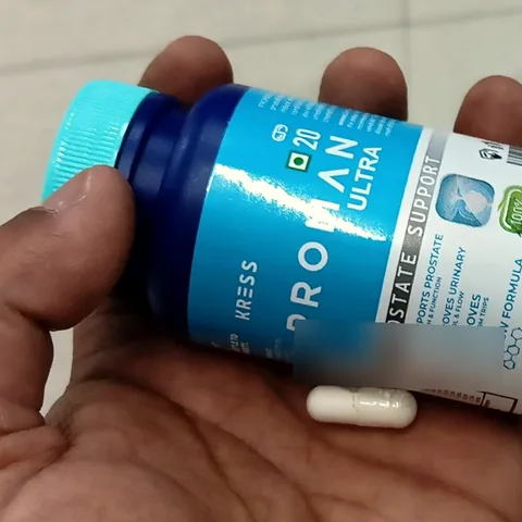 Close view of the Proman Ultra bottle label held in a hand with one capsule